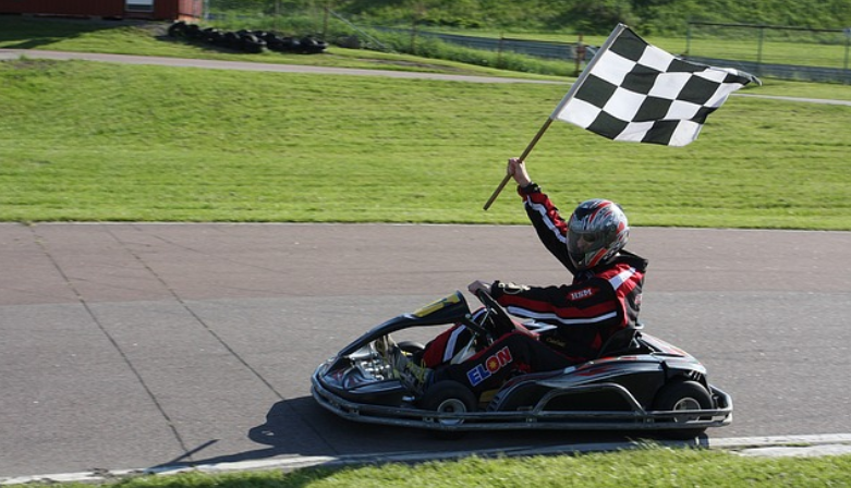 Man in go kart with chequered flag